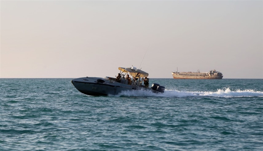 قارب تابع لخفر السواحل اليمني وخلفه سفينة شحن تبحر في البحر الأحمر (أرشيف)