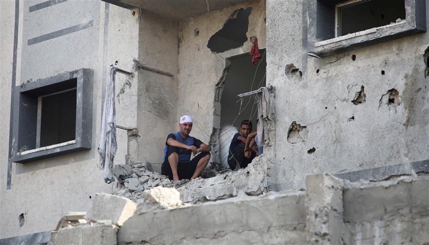 فلسطينيان يجلسان على أنقاض منزلهما في رفح (رويترز)