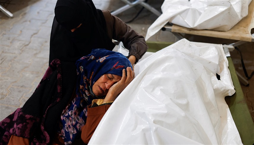 امرأة تبكي بجانب جثة فلسطيني قُتل في غارات إسرائيلية على رفح (رويترز)