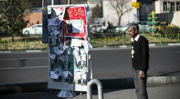 رجل إيراني يقف امام ملصقات مرشحين للانتخابات البرلمانية في طهران (أ ف ب)