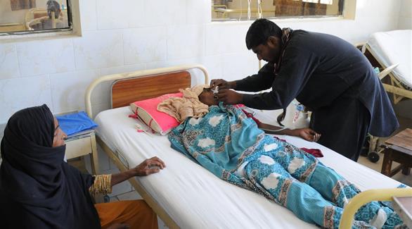 طبيب يعالج إحدى النسوة بعد تناولها السكاكر الملوثة في باكستان (اي بي ايه)