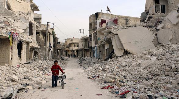 طفل يتجول بين المباني المدمرة إثر القصف في حلب (أرشيف)