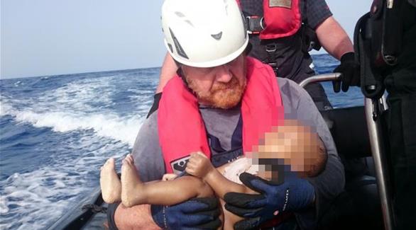 عامل الإنقاذ وبيده الطفل الغريق (سي ووتش / رويترز)