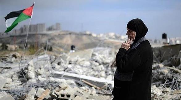 إمرأة فلسطينية تقف على أنقاض المنازل التي هدمها الاحتلال الإسرائيلي (أرشيف)