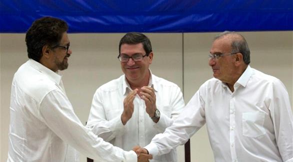 ممثلا الطرفان المتنازعان يتصافحان وسط تصفيق وزير الخارجية الكولومبي (أ ب)