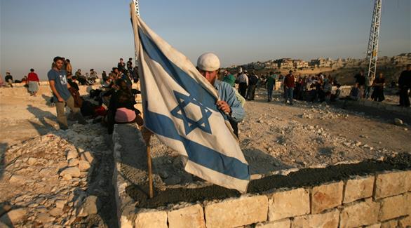 مستوطن يهودي يرفع علم الاحتلال فوق مستوطنة يتم بناؤها في الضفة الغربية عام 2007. (أرشيف)