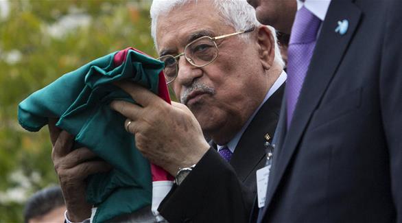 الرئيس عباس مقبلاً العلم الفلسطيني (ريكس)