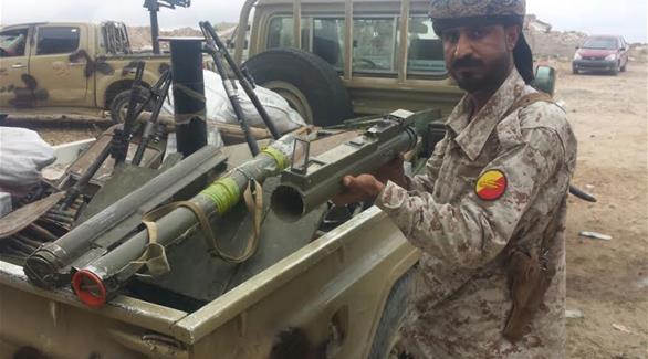 جندي من قوات الحزام الأمني بجانب مركبة عسكرية تحمل الأسلحة المصادرة (24)