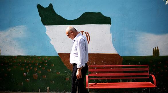 رجل يمر بالقرب من خريطة إيران مرسومة على الحائط (أرشيف / غيتي)