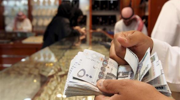 رجل يعد نقوده داخل أحد متاجر الذهب في الرياض (أرشيف / رويترز)