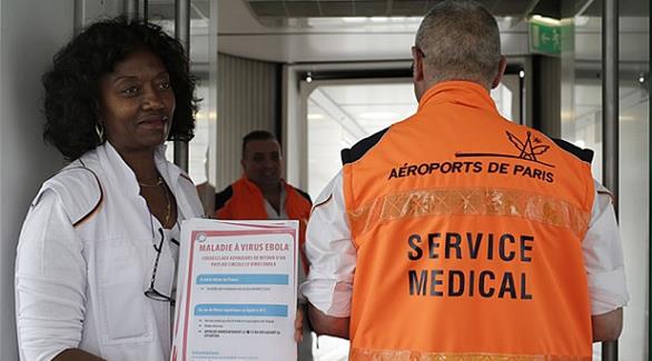 موظفة بمطار تشارل دي غول الفرنسي تحمل نشرة معلومات حول إيبولا(أ ف ب)