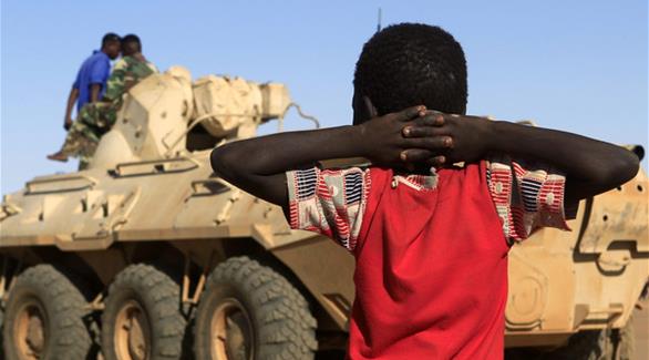 صبي ينظر نحو قافلة عسكرية للقوات الحكومية المصاحبة للمدعي الخاص بجرائم دارفور(رويترز)