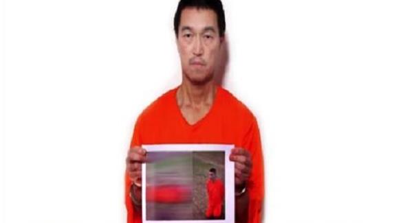 الرهينة الياباني كينجي جوتو مع صورة للرهينة الأخر مذبوحاً من قبل داعش (أرشيف)