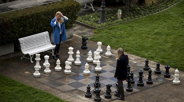 صحافيتان من روسا تلعبان الشطرنج العملاق في فناء فندق قصر البوريفاج في لوزان حيث تقام المحادثات النووية (رويترز)