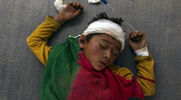صبي مصاب ينام على الأرض خارج مستشفى دادينغ المكتظة عقب زلزال النيبال (رويترز)