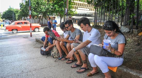 كوبيون يستخدمون الإنترنت إلى جانب فندق "هابانا ليبري" بالعاصمة الكوبية (أ ف ب)