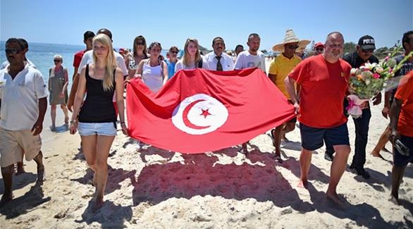 سياح يحملون العلم التونسي وورود على شاطئ سوسة
