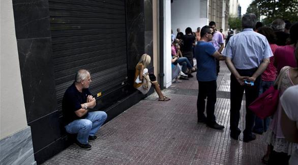 اليونانيون يتجمعون خارج أحد البنوك لسحب أموالهم في ظل الأزمة التي تعيشها البلاد، في 28 يونيو(أ ف ب)