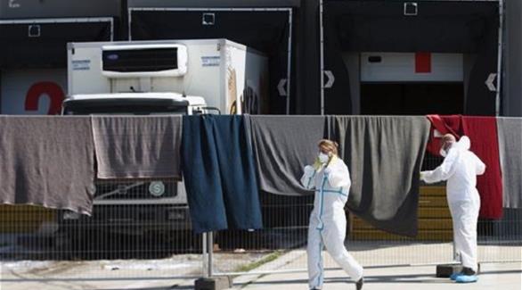 أطباء الطب الشرعي امام الشاحنة التي وجدت فيها جثث المهاجرين في النمسا (رويترز)