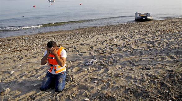 مهاجر يبكي بعد وصوله إلى شاطئ الأمان ويظهر نوع القارب الذي استخدم 