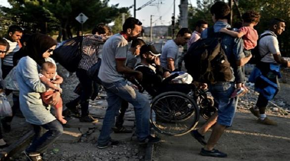 أبوفهد على كرسيه مدفوعاً من لاجئين آخرين على الحدود المقدونية اليونانية (لوبوان)