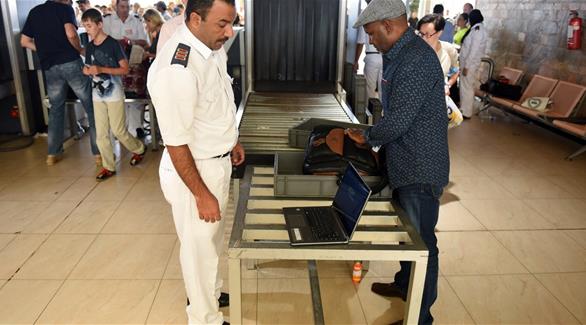 عنصر أمني في مطار القاهرة متفقداً ممتلكات أحد الركاب