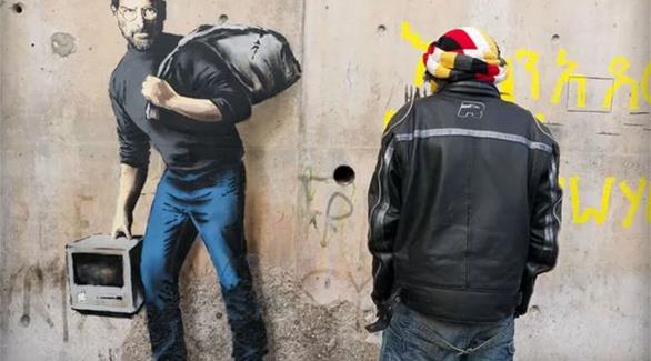 لوحة "ستيف جوبز" على جدار مخيم "كاليه" الفرنسي لحث الأوروبيين على استقبال اللاجئين السوريين بترحاب 