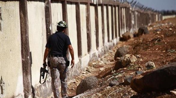 مقاتل من الجيش السوري الحر يمشي بمحاذاة سور مطار منغ العسكري(رويترز)