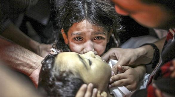 طفلة فلسطينية تحضن طفلاً آخر قُتل على يد جيش الاحتلال الإسرائيلي(أرشيف)
