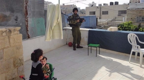 جندي اسرائيلي على شرفة إحدى المنازل في فلسطين