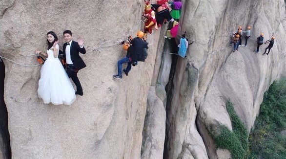 العروسان وهما يلتقطان الصور على حافة الجبل (ميرور)