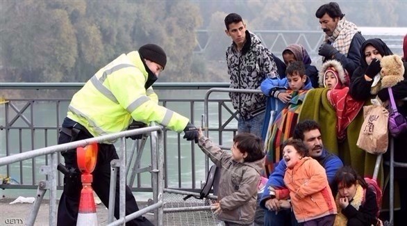 شرطي ألماني يصافح طفلا لاجئاً ينظر مع عائلته عبور الحدود النمساوية الألمانية (أرشيف)