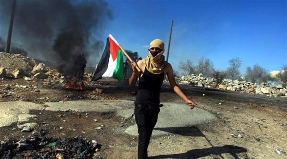 متظاهر يحمل العلم الفلسطيني في اشتباكات ضد الجيش الإسرائيلي (أرشيف)