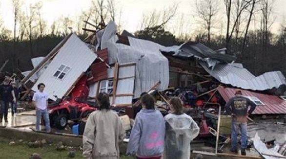 عائلة أمريكية تنظر إلى بيتها المحطم جراء العواصف (تويتر)