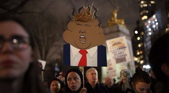 متظاهرة تحمل صورة معدلة للرئيس دونالد ترامب 
