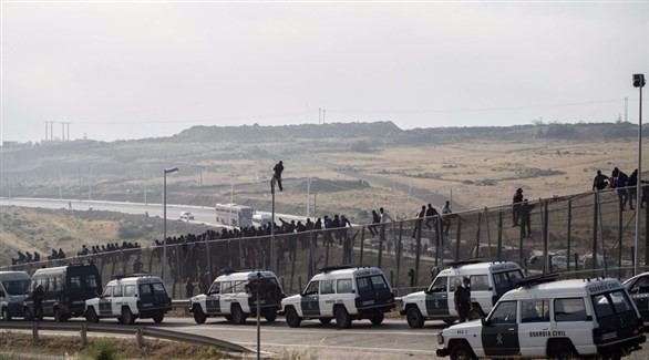 مهاجرين يتسلقون السياج الحدودي بين إسبانيا والمغرب (أرشيف)