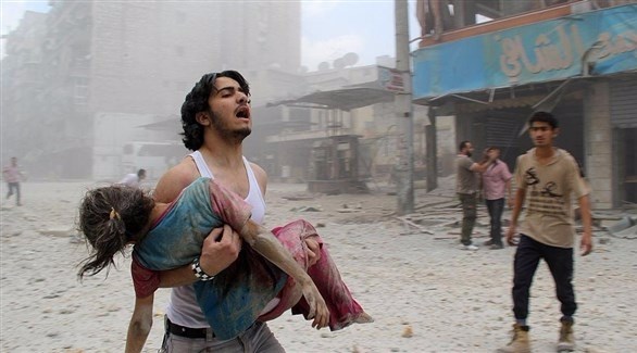 شاب يحمل فتاة أصيبت بجروح في قصف ببراميل متفجرة في حلب.(أرشيف)