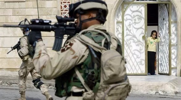 فتاة عراقية تراقب جندياً أمريكياً يطلق النار. (أف ب)