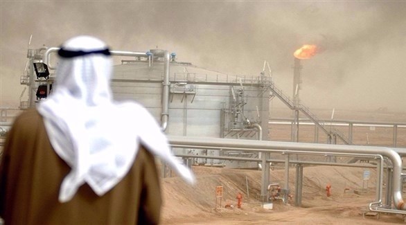 رجل يقف قبالة نقطة لاستخراج النفط