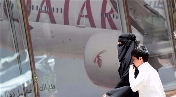 امرأة سعودية وابنها يمران بمكتب الخطوط الجوية القطرية في الرياض. (أف ب)