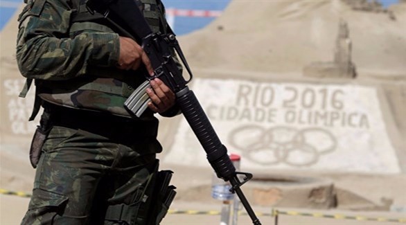 عسكري برازيلي يقف إلى جانب منحوتة رميلة للألعاب الأولمبية (أرشيف)