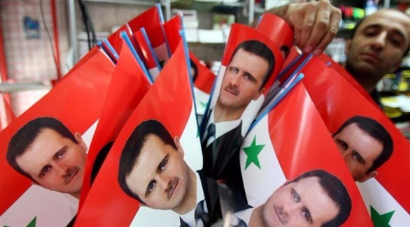 سوري يبيع أعلاماً عليها صورة الرئيس بشار الأسد.(أرشيف)