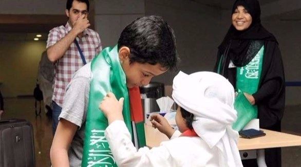 طفلان إماراتيان يضعان الوشاح الأخضر حول عنقيهما احتفالاً باليوم الوطني السعودي.(أرشيف)