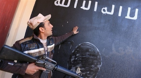 جندي عراقي ينظر إلى جدار رسم عليه علم داعش في العرقوب بالعراق.(أرشيف)