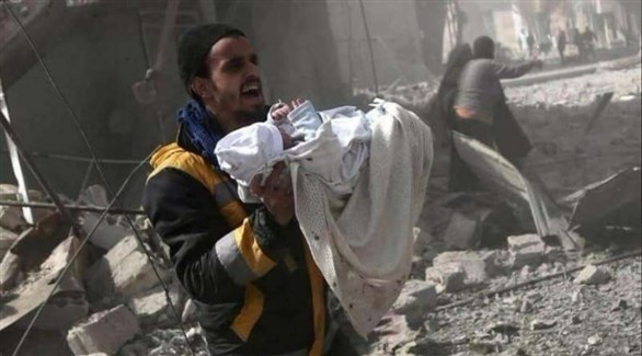 سوري يُجلي طفلاً أصيب في غارة على الغوطة (تويتر)