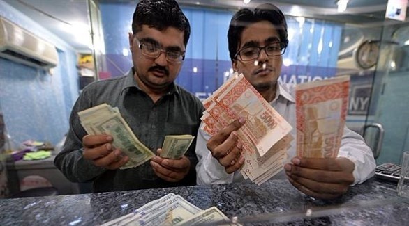 رجلان داخل أحد محلات تحويل العملات في باكستان (غيتي)