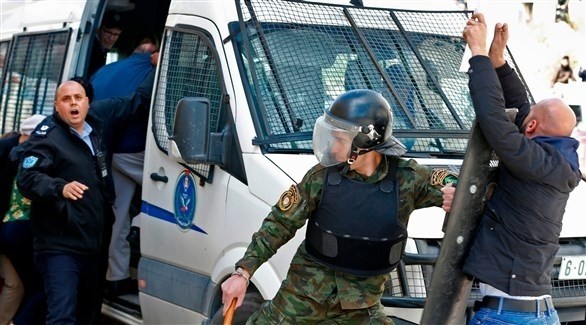 شرطي فلسطيني يمنع محتجاً من الاقتراب من حافلة الوفد الأمريكي (أ ف ب)