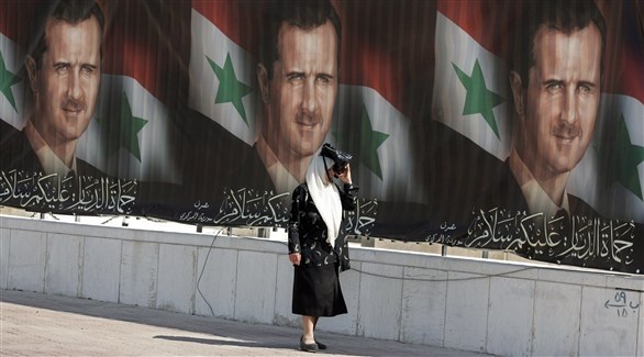 امرأة تمر بجانب صوراً للأسد في دمشق (أ ف ب)