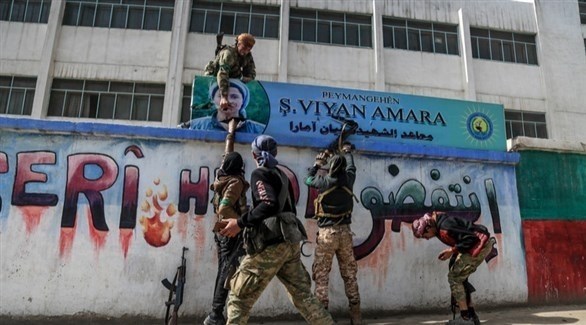 عناصر من الجيش السوري الحر في عفرين ينزعون لافتات كردية في على جدران المدينة (إ ب أ)