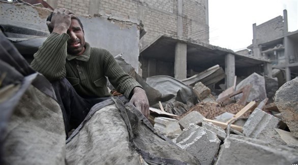 مدني يجلس بين أنقاض بيت مدمر في الغوطة الشرقية (أ ف ب)